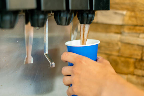 Photo of hand holding a paper glass to pour the lemonade soda soft drink  machine  in a fastfood restaurant