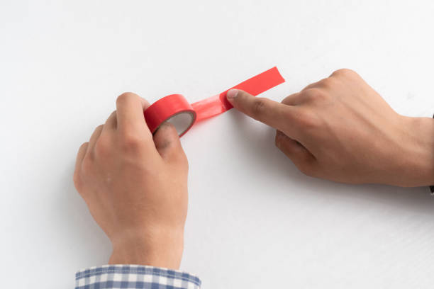 istock hands holding an adhesive color tape and apply it to the white surface 1163129314