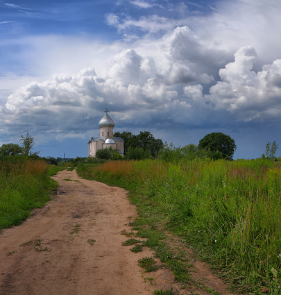 Picturesque Russian landscape with a country road to the Church