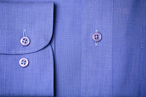 Sleeve and butons detail on a blue elegant shirt.