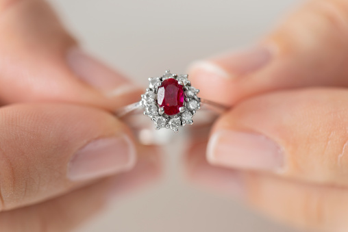 Hands holding diamond ring. Ruby.