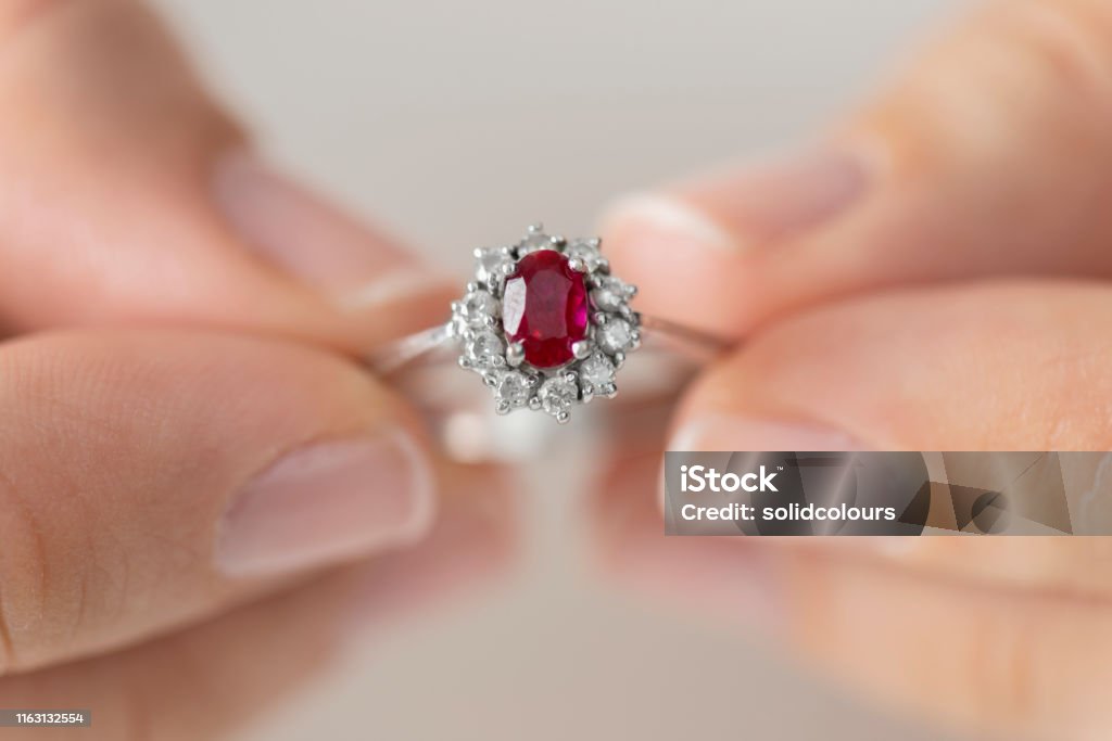 Woman Holding a Diamond Ring Hands holding diamond ring. Ruby. Ruby Stock Photo