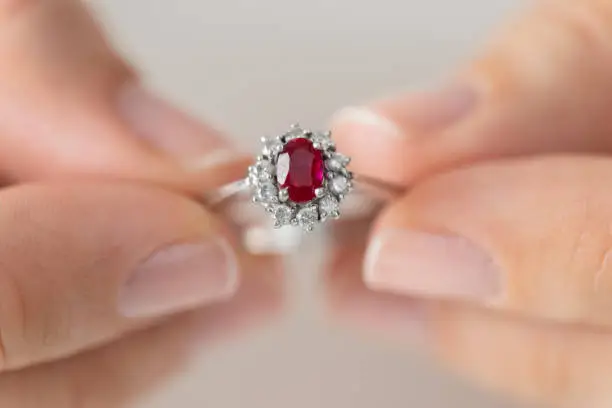 Hands holding diamond ring. Ruby.