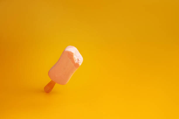 istock pink ice cream popsicle on yellow background bitten off a piece 1163133858
