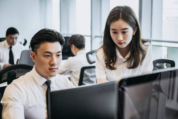 istock Young Chinese office workers in business attire at computers 1163139155