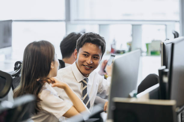 istock Young Chinese businesspeople conversing at workstation 1163139196