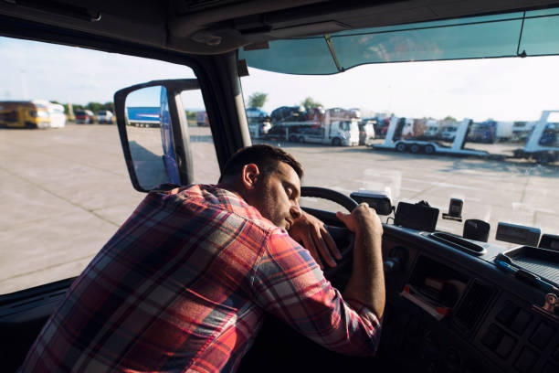 彼の小屋で眠っている疲れたトラックの運転手。白人男性の運転手がハンドルで眠りに落ちる。残業。 - truck semi truck blue truck driver ストックフォトと画像