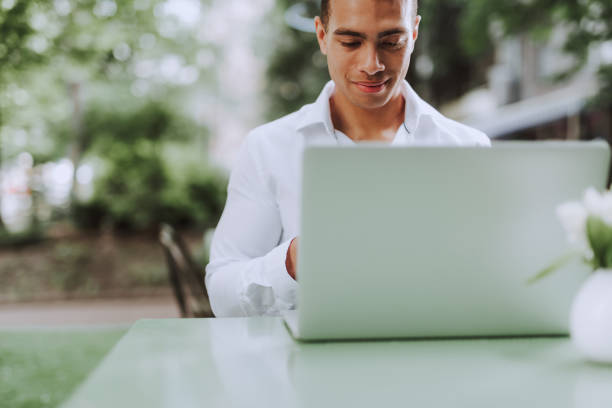istock Handsome young man in classic white shirt using modern laptop 1163144253
