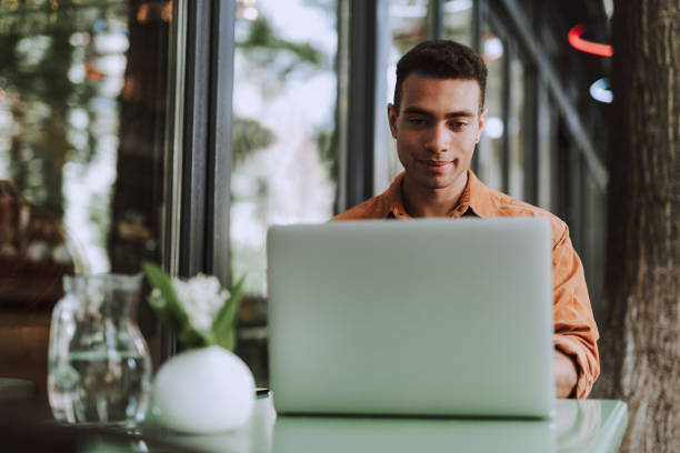 istock Handsome young man sitting at the table and using laptop 1163144269