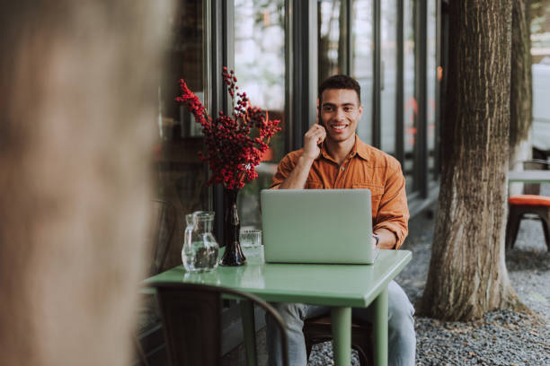 istock Handsome young man with modern notebook talking on cellphone 1163144295