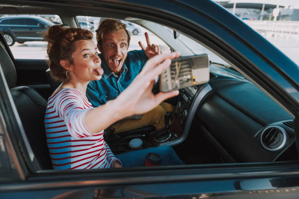 istock Cheerful young couple making selfie in car 1163152752