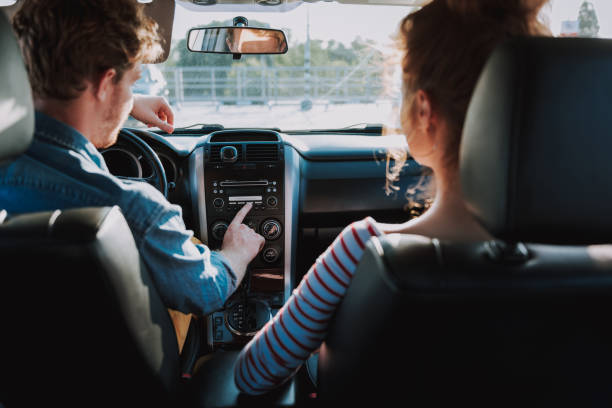 istock Young man using car audio stereo system while sitting in car with lady 1163152774