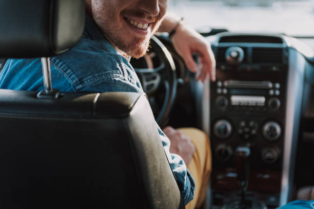istock Cheerful young man sitting in his car 1163153048