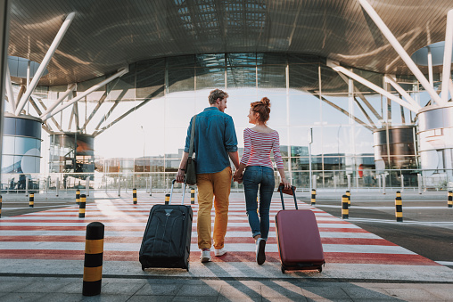 Hermosa pareja amorosa con maletas de viaje que se llevan de la mano en el aeropuerto photo