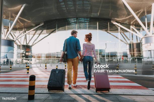 Beautiful Loving Couple With Travel Suitcases Holding Hands In Airport Stock Photo - Download Image Now