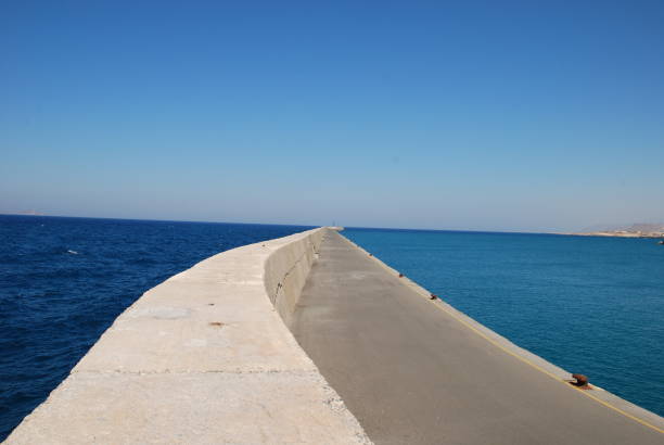 istock Long stone pier stretching into the blue sea 1163153852