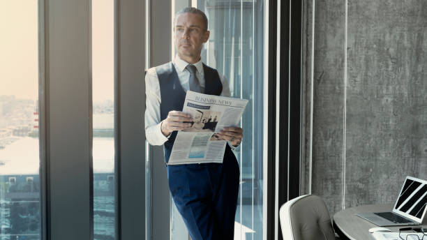 istock Businessman reading newspaper at office 1163155205