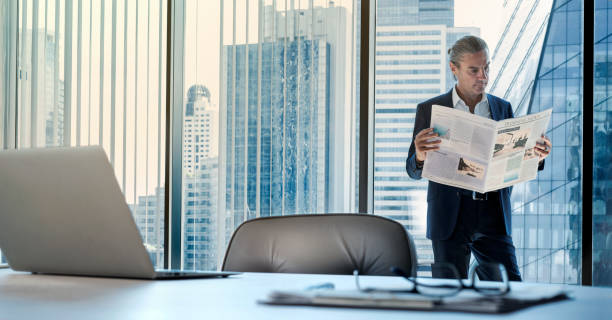 istock Businessman reading newspaper at office 1163155206