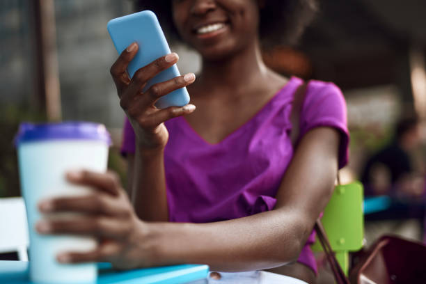 istock Happy young woman using mobile in cafe outdoors 1163156833
