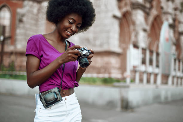 istock Smiling young afro-american woman using retro camera on the street 1163156849