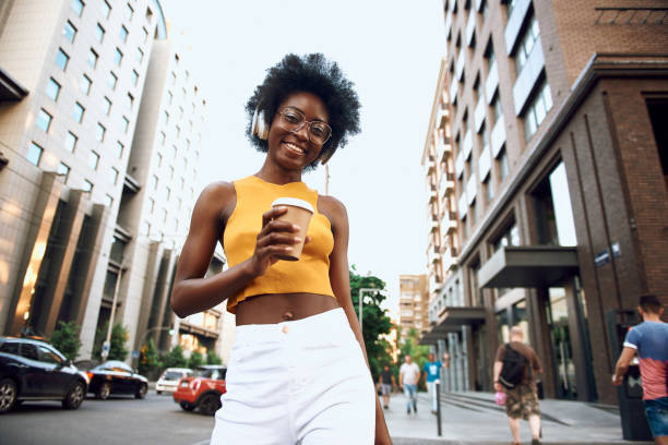 istock Smiling young lady holding coffee on the street 1163158761