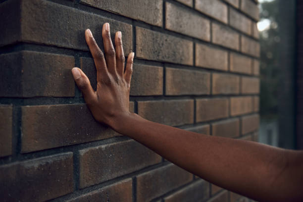 istock Woman hand is touching a brick wall 1163158876