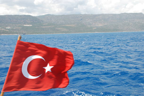 istock Turkish flag on blue mediterranean sea shape 1163159632