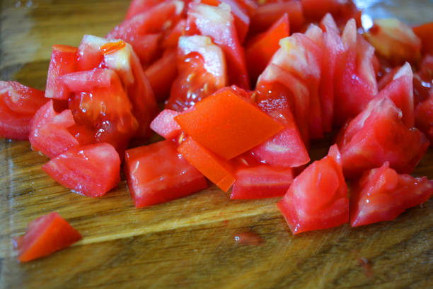 istock Fresh red tomatoes chopped into small pieces on a wooden brown plank. 1163160517