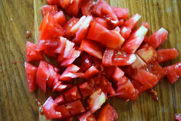 istock Fresh red tomatoes chopped into small pieces on a wooden brown plank. 1163160520