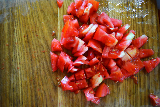 istock Fresh red tomatoes chopped into small pieces on a wooden brown plank. 1163161039