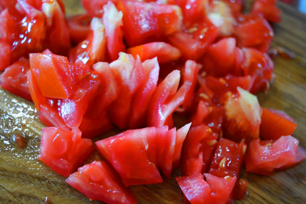 istock Fresh red tomatoes chopped into small pieces on a wooden brown plank. 1163161040