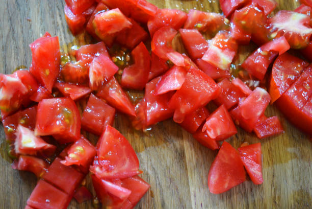 istock Fresh red tomatoes chopped into small pieces on a wooden brown plank. 1163161055