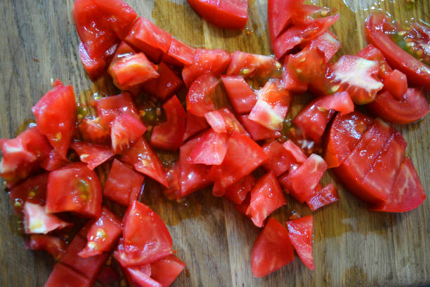 istock Fresh red tomatoes chopped into small pieces on a wooden brown plank. 1163161058