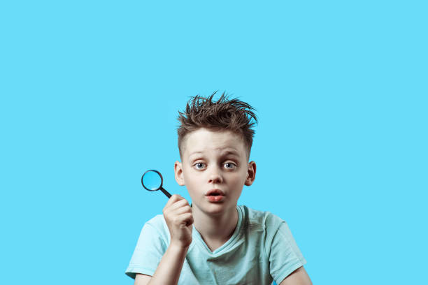 istock a boy in a light t-shirt holding a small magnifying glass on blue background 1163162714