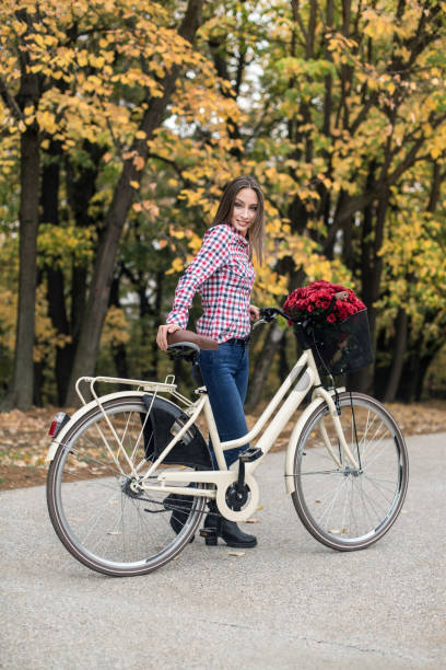 istock Young woman riding a bicycle in park 1163164319