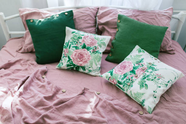 istock Pink linen bed with decorative green pillows. 1163172013
