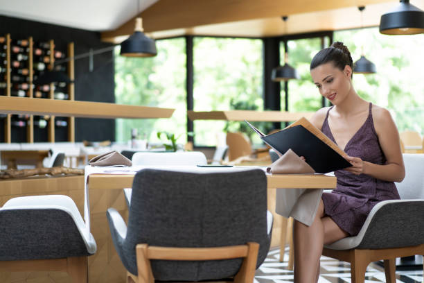 istock Elegant woman looking at menu in restaurant 1163174736