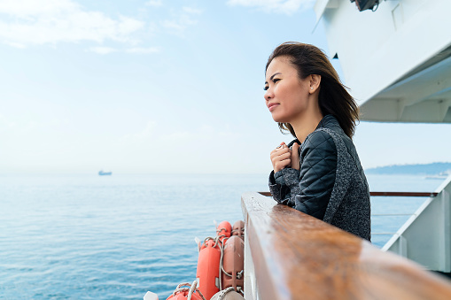 Asian Woman travelling by ferry, getting away from it all - hope concept