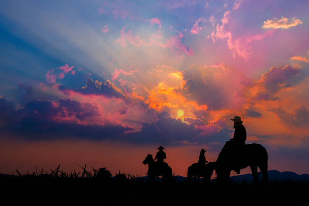 Cowboy on horseback with views of the mountains and the sunset sky. stock photo