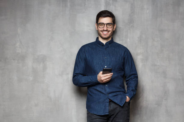 istock Man standing with cellphone in hands, isolated on grey background 1163183118