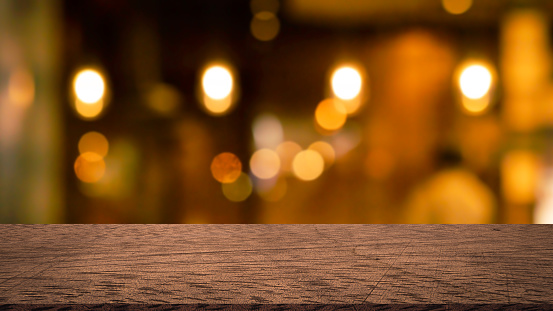 abstracto borroso moderno interior cafetería cafetería decorar con bombillas lámpara de luz en el techo y la perspectiva de la mesa de mostrador de madera vintage para mostrar, promover, anunciar el producto en el concepto de montaje de la pantalla photo