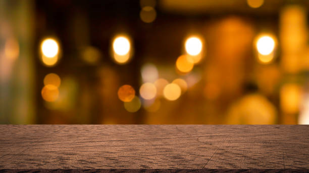 abstracto borroso moderno interior cafetería cafetería decorar con bombillas lámpara de luz en el techo y la perspectiva de la mesa de mostrador de madera vintage para mostrar, promover, anunciar el producto en el concepto de montaje de la pantalla - mesa de comedor fotografías e imágenes de stock
