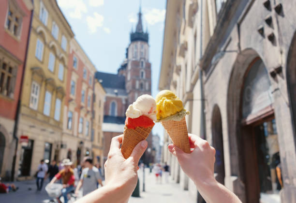 Women's hands with ice cream on the background of the city sights Mariatsky church in the historical center of Krakow, Poland, Europe, a famous tourist place stock photo