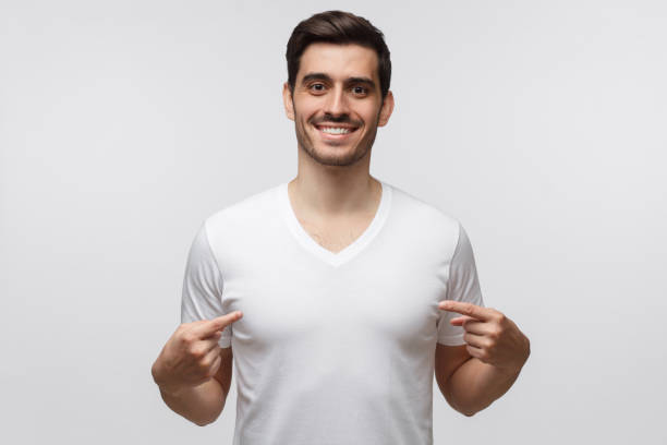 istock Young man pointing to his white t-shirt with fingers, showing empty space for your text, isolated on gray background 1163192132