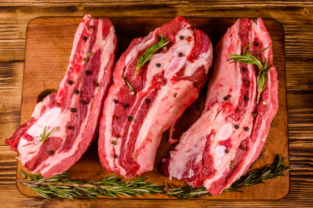 istock Raw pork ribs with spices and rosemary on a cutting board. Top view 1163192590