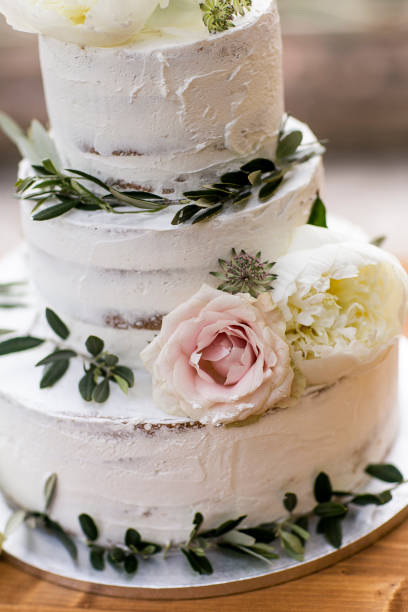 istock Naked wedding cake in boho chic style decorated with olive branches, pink roses and white peonies. 1163192842