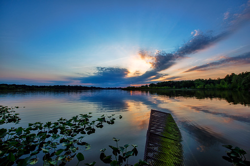 The sunset over tranquil water with broken dock.