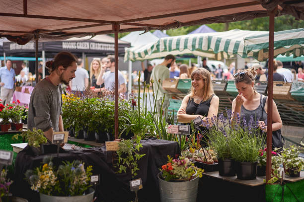 giovani che fanno shopping di fiori e piante in una bancarella di fiori nel mercato di brockley, un mercato contadino locale che si tiene ogni sabato nel sud-est di londra. - southeast england foto e immagini stock