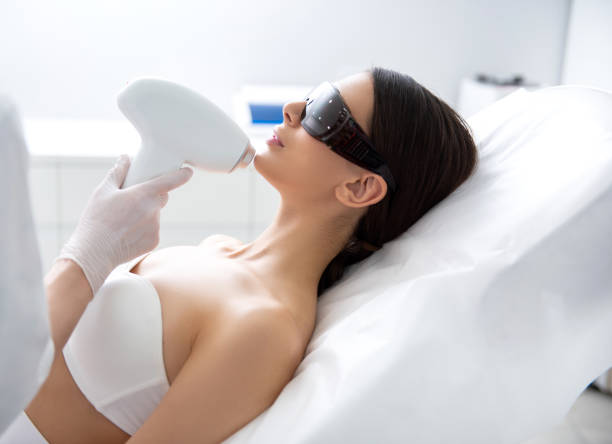 Young female on chin laser epilation procedure Aesthetic face treatment. Close up side on portrait of young woman having professional laser hair removal procedure in chin zone while lying on couch hair removal photos stock pictures, royalty-free photos & images