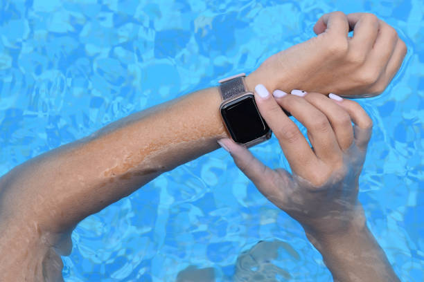 Womans hands with smarthwatch in swimming pool stock photo